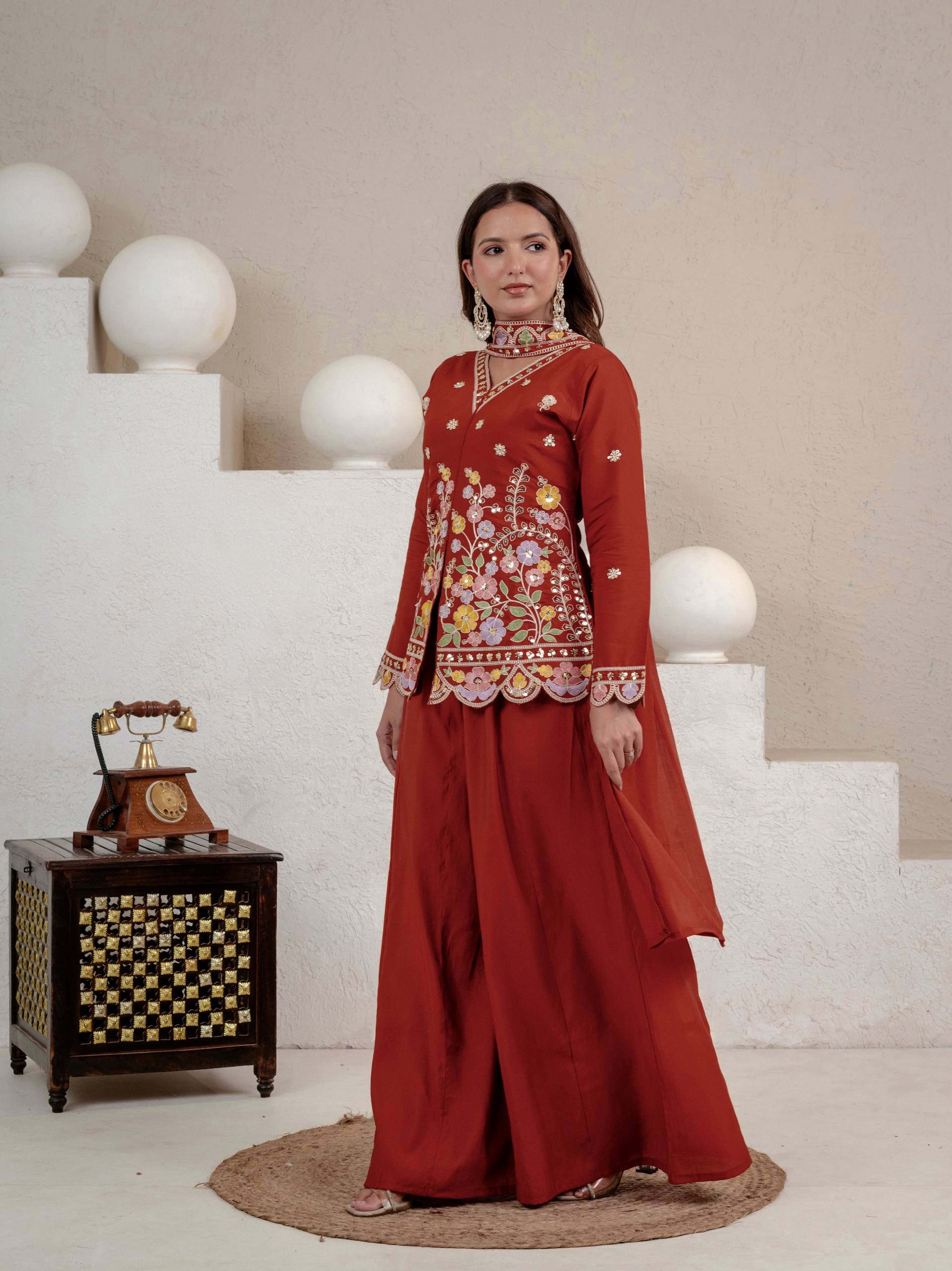 Resplendent Rust Orange Peplum Kurti and Flared Palazzo Suit Set Adorned with Intricate Multicolored Floral Embroidery, Sequin Accents, and Ornate Scalloped Borders